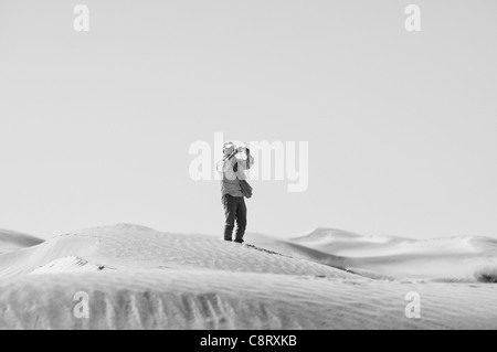 Africa, Tunisia, nr. Tembaine. Desert traveller photographing in the dunes close to Tembaine on the eastern edge of the Grand... Stock Photo