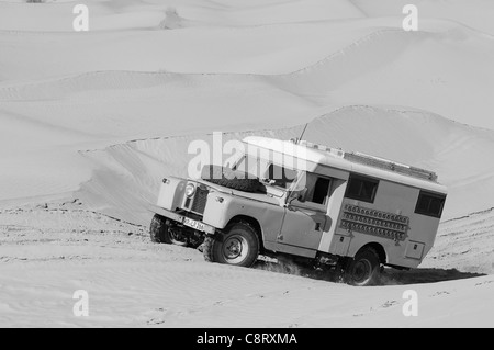 Africa, Tunisia, nr. Tembaine. Desert traveller driving an ex-army 1966 Land Rover Series 2a Ambulance camper conversion ... Stock Photo