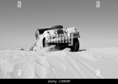 Africa, Tunisia, nr. Tembaine. Desert traveller driving his 1964 Land Rover Series 2a Truck Cab through a sandfield close to ... Stock Photo