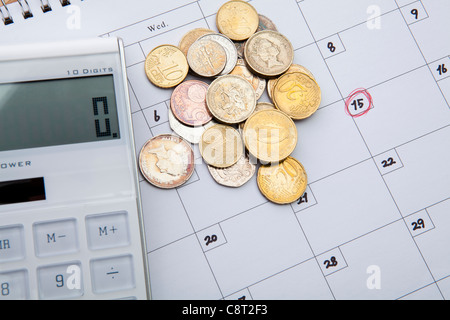 Top view of calculator and coins on calendar Stock Photo