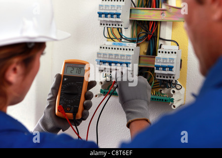 electrician and his apprentice working on a fuse board Stock Photo