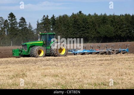 Big tractor pull a plough on a late summer stubble field. Southern Zealand, Denmark. Stock Photo