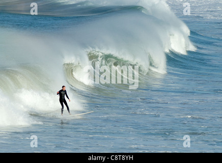 A surfer surfing a breaking wave with lots of water spray in Newquay, Cornwall UK. Stock Photo