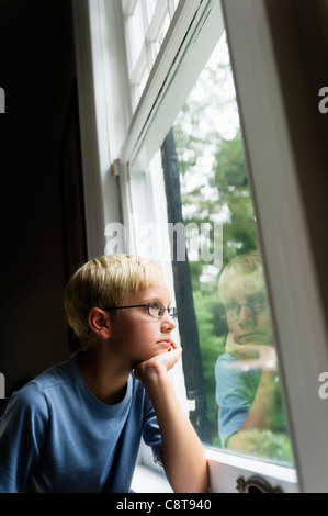 USA, New York, Old Westbury, Boy looking out window Stock Photo