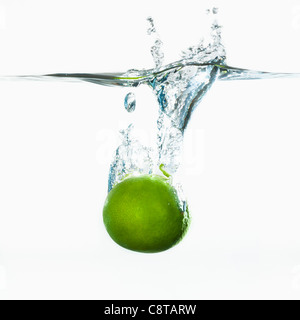 Studio shot of green apple falling into water Stock Photo