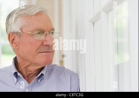 USA, New York State, Old Westbury, Portrait of senior man looking through window Stock Photo