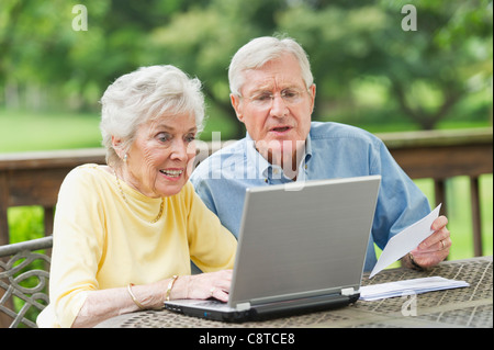 USA, New York State, Old Westbury, Senior couple using laptop on porch Stock Photo