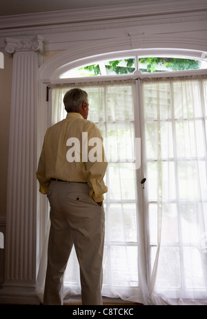 USA, New York State, Old Westbury, Senior woman looking through window Stock Photo