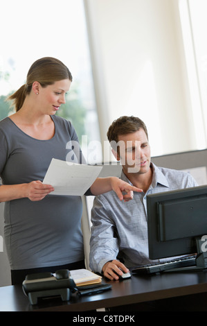 USA, New Jersey, Jersey City, Young pregnant woman working with colleague in office Stock Photo