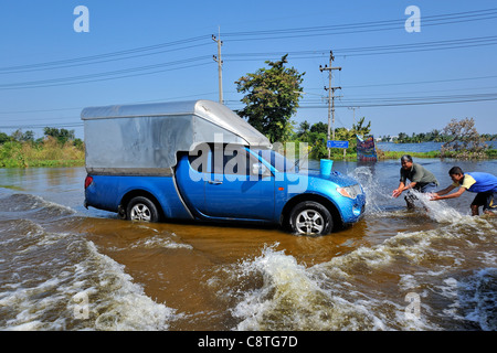 Thai men washing their pickup truck with floodwater, Thailand was hit by severe flooding in 2011 Stock Photo