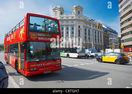 Red double-deck tour bus with open top drives up the Passeig de Gracia in Barcelona, Catalonia, Spain. Stock Photo