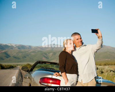 USA, Utah, Kanosh, Mid adult couple photographing themselves in front of majestic mountain range Stock Photo