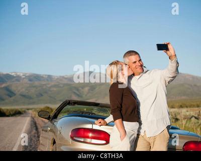 USA, Utah, Kanosh, Mid adult couple photographing themselves in front of majestic mountain range Stock Photo