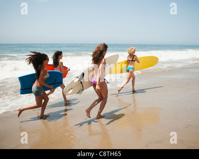 USA, California, Malibu, Group of young attractive women running into water with surfboards Stock Photo