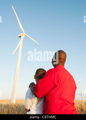 USA, Oregon, Wasco, Father and son standing in wheat field, watching wind turbine Stock Photo