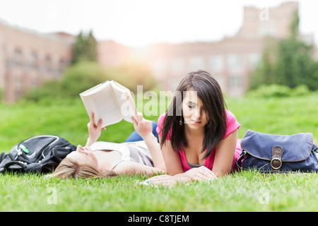 USA, Washington, Seattle, Two female college student lying on grass reading books Stock Photo