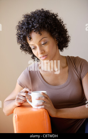 USA, California, Los Angeles, Young woman sitting in armchair holding cup Stock Photo