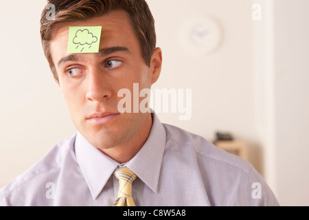 Businessman with adhesive note attached on forehead Stock Photo