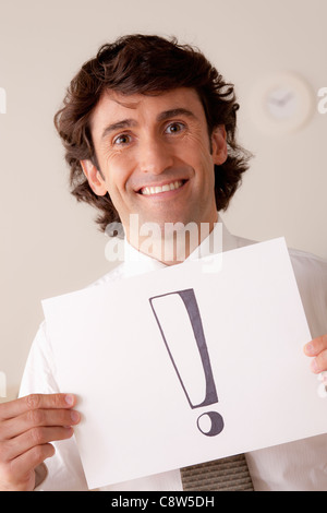 Studio portrait of businessman holding sheet of paper with exclamation mark Stock Photo