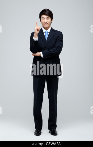 Portrait Of Smiling Asian Businessman Pointing With Finger Stock Photo