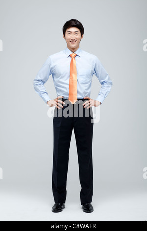 Portrait Of Smiling Asian Businessman With Hand On Waist Stock Photo