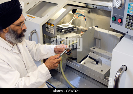 CNC lathe operator checking a job with a micrometer Stock Photo