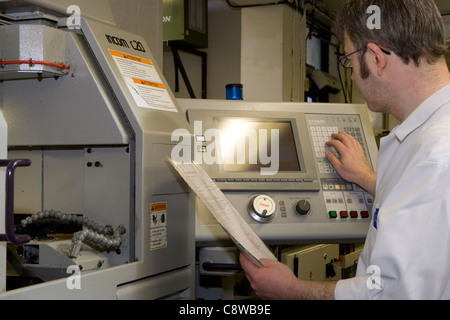 CNC lathe operator programming in data & setting up a task Stock Photo