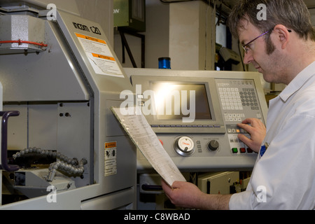 CNC lathe operator programming in data & setting up a task Stock Photo