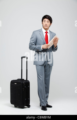 Asian Businessman With Luggage Holding Newspaper Stock Photo