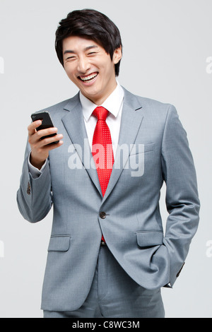Laughing Asian Businessman Using Cell Phone Stock Photo