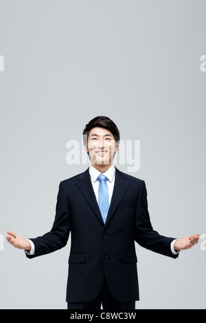 Portrait Of Smiling Asian Businessman Standing With Palms Up Stock Photo