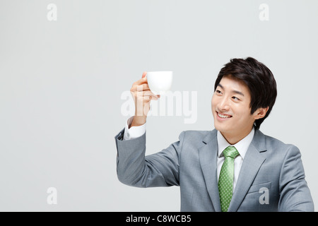 Asian Businessman Looking At Coffee Cup Holding In Hand Stock Photo