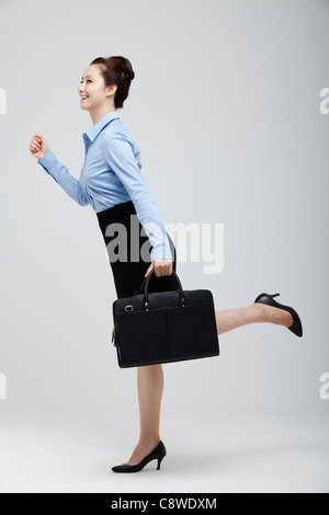 Asian Businesswoman In Hurry Holding Suitcase In Hand Stock Photo