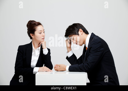 Asian Businesswoman Looking At Depressed Businessman Stock Photo