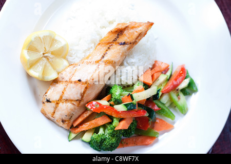 Fillet of salmon baked with our maple glaze, served on a bed of aromatic basmati rice with stir fry vegetables. Stock Photo