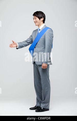 Portrait Of Asian Businessman Extending Hand Wearing Sash Stock Photo