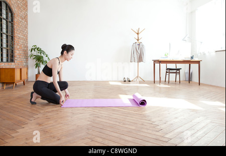 Asian Woman Arranging The Exercise Mat On Harwood Floor Stock Photo