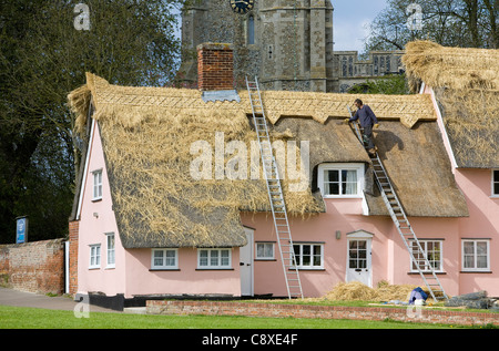 Thatcher working on thatched cottage roof in Cavendish, Suffolk UK Stock Photo
