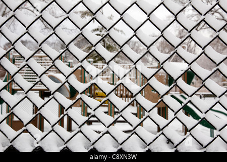Snow covered chain link fence, playground in background. Christmas morning 2010 Lindberg Park, Oak Park, Illinois Stock Photo