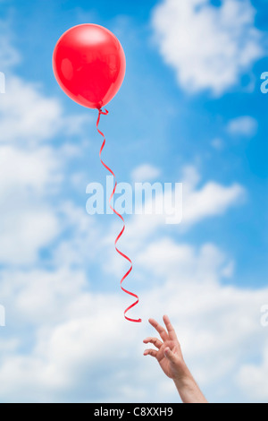 USA, Illinois, Metamora, hand reaching for red balloon Stock Photo