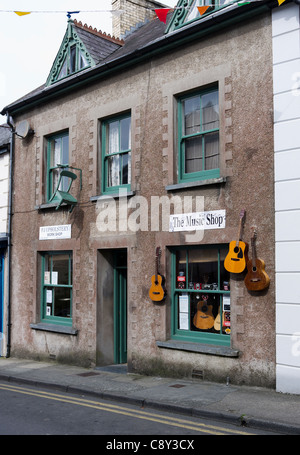 Guitars and chairs hanging on the wall outside The Music and upholstery shops in Narberth, Pembrokeshire, Wales Stock Photo