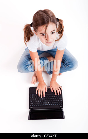 Top view of a little girl sitting on floor working with a laptop Stock Photo