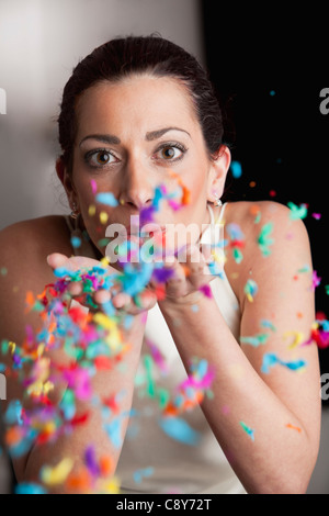 Woman blowing confetti of her hands Stock Photo