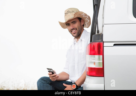 portrait of young man wearing straw hat with mobile phone Stock Photo