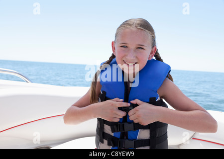 USA, Florida, St. Petersburg, Portrait of smiling girl (10-11) fastening life jacket in speedboat Stock Photo