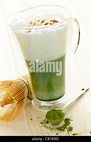 Matcha green tea latte beverage in glass mug with whisk Stock Photo