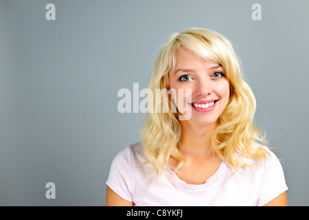 Portrait of smiling young blonde caucasian woman on grey background Stock Photo