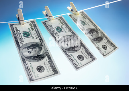 Hundred dollar bills drying on a clothes line isolated on blue sky background Money laundering concept Stock Photo
