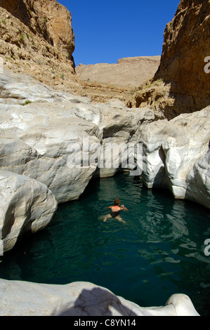 Visitor swimming in a cave pool in a canyon of the Wadi Bani Khalid, Sultanate of Oman Stock Photo