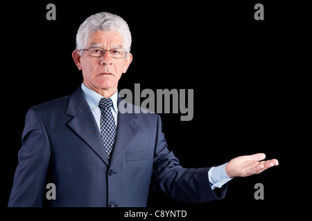 senior businessman showing something with his hands (isolated on black Stock Photo